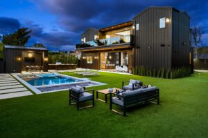 Modern luxury home with pool and outdoor seating at dusk.